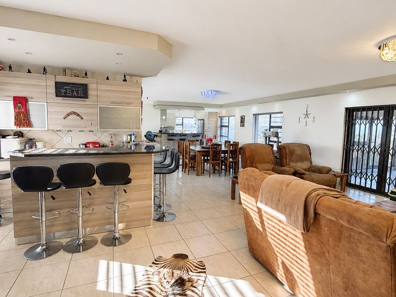 Spacious open-plan living area featuring a built-in bar, tiled flooring, and modern lighting, seamlessly connecting the lounge and dining spaces.