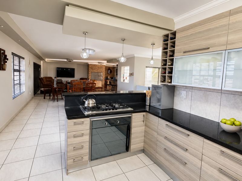 Spacious open-plan kitchen and living area featuring modern cabinetry, granite countertops, integrated gas hob, and tiled flooring throughout.