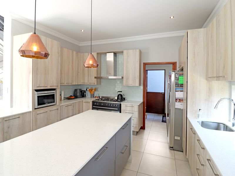 Modern kitchen featuring light wood cabinetry, a central island with quartz countertops, gas stove, and high-quality finishes throughout.