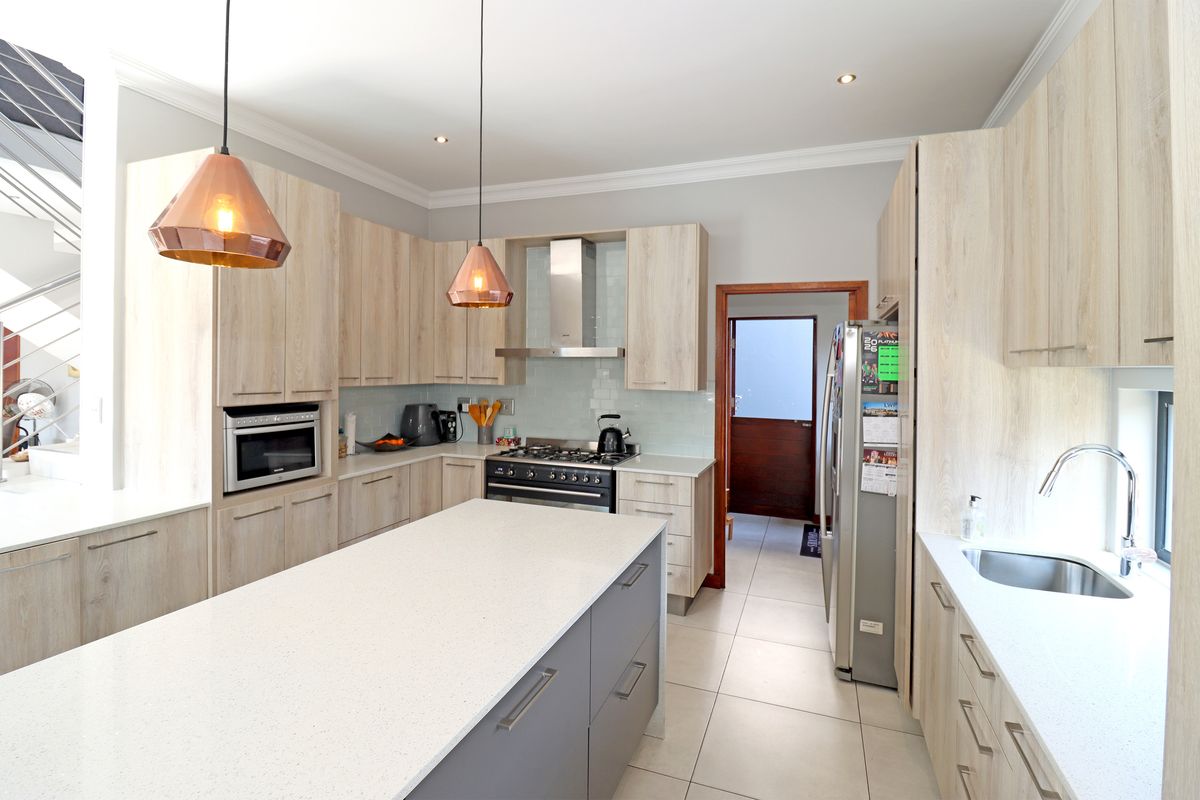 Modern kitchen featuring light wood cabinetry, a central island with quartz countertops, gas stove, and high-quality finishes throughout.