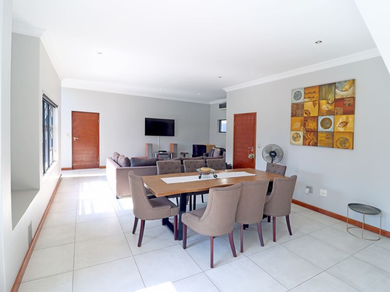 Spacious open-plan living and dining area featuring neutral wall tones, large format floor tiles, and recessed ceiling lighting.