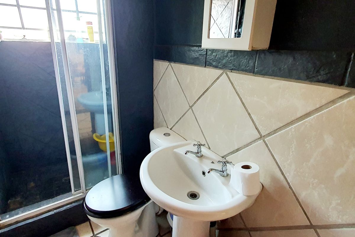 A compact bathroom featuring a pedestal basin, toilet, and a shower enclosure with sliding glass doors and tiled walls.
