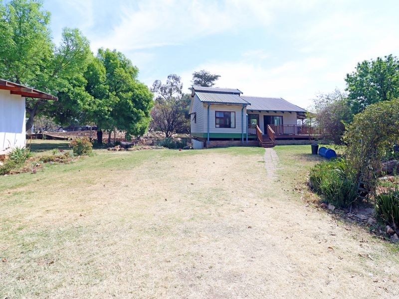 Rear view of the farm cottage featuring a timber deck, metal roofing, and a spacious garden area.