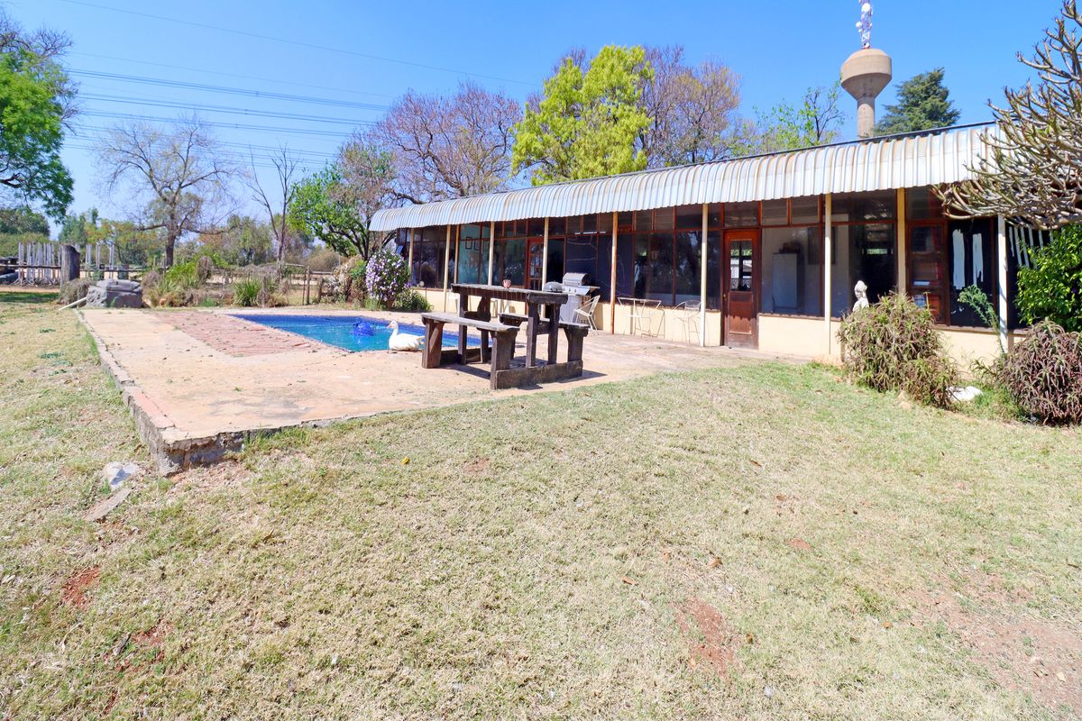 Rear exterior view of the farm property featuring a swimming pool, a covered patio area, and a water tower structure.