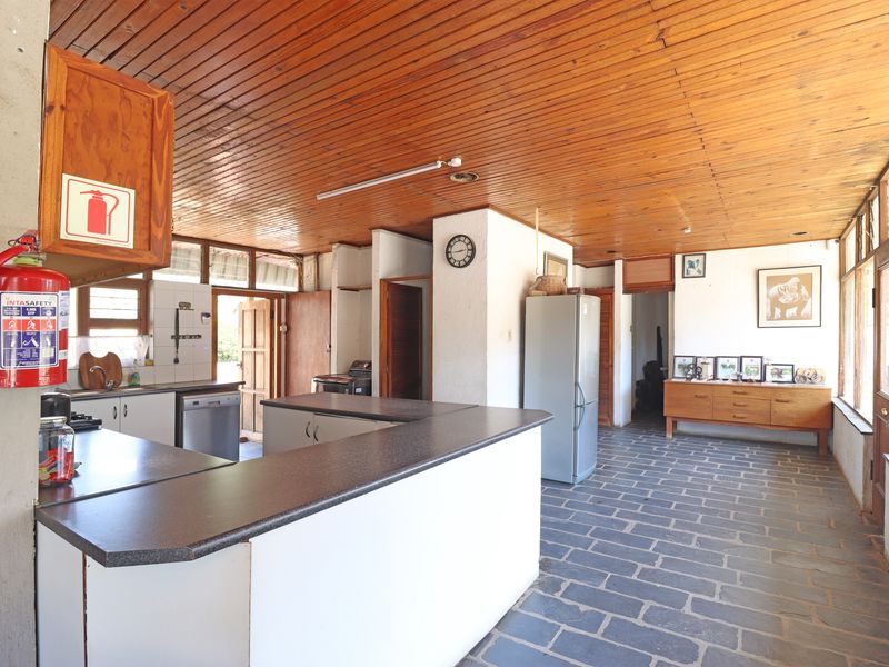 Spacious kitchen featuring slate tile flooring, a timber tongue and groove ceiling, and ample built-in cabinetry with laminate countertops.