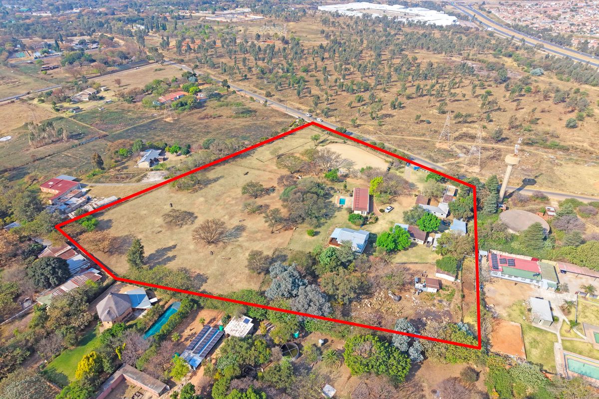 Aerial view of a large farm property featuring multiple structures, a swimming pool, and expansive grounds outlined in red.