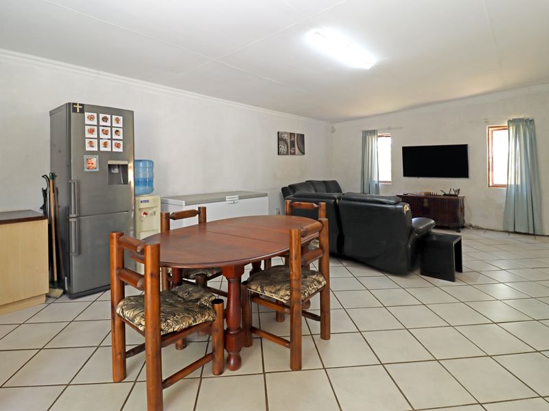 Open-plan living and dining area featuring tiled flooring and neutral walls, offering a functional space with potential for modern updates.