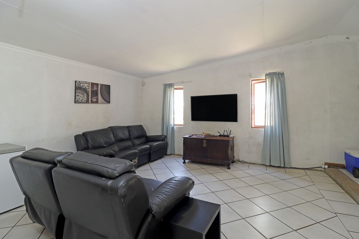 A living room featuring tiled flooring and wall-mounted television, requiring cosmetic updates to the wall finishes.