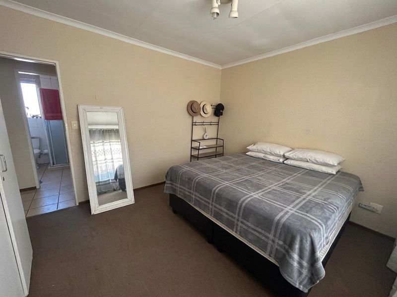 A standard bedroom featuring carpeted flooring, cove cornicing, and an en-suite bathroom access point.