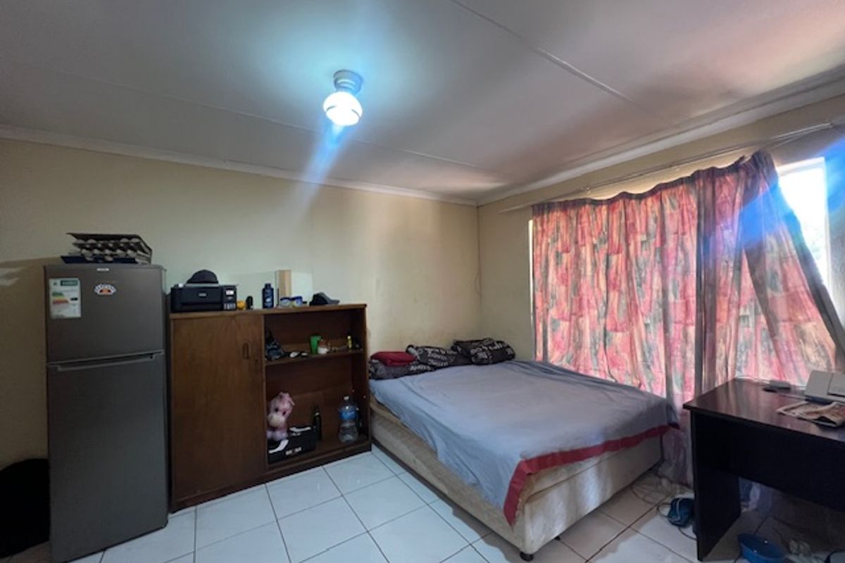 A bedroom featuring tiled flooring and basic finishes, requiring cosmetic updates to improve its overall appeal and condition.