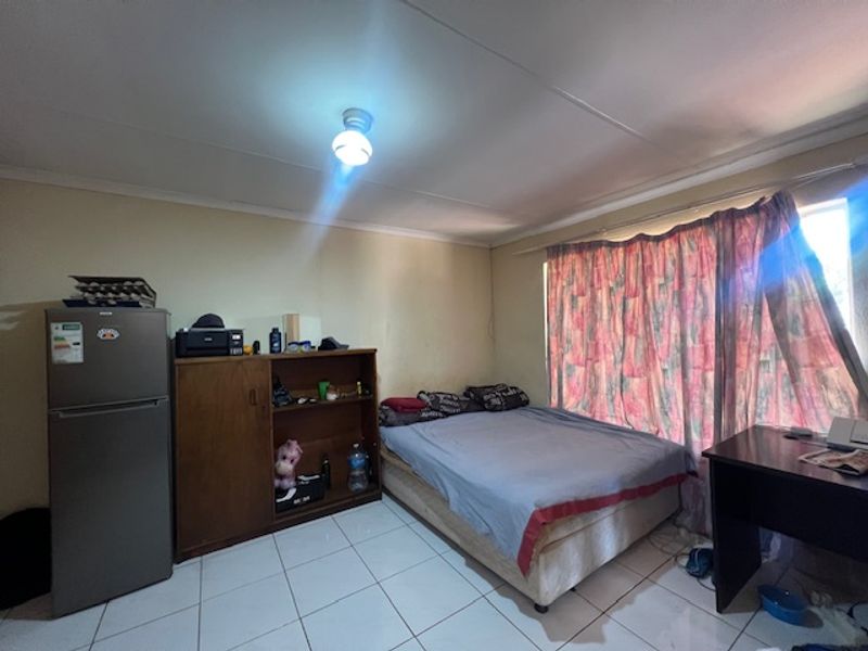 A bedroom featuring tiled flooring and basic finishes, requiring cosmetic updates to improve its overall appeal and condition.