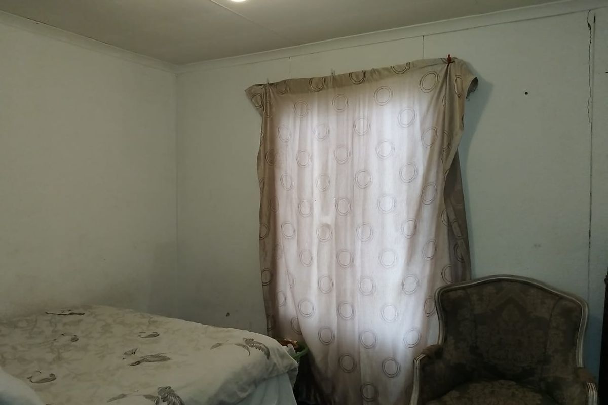 A bedroom featuring plain walls with visible structural cracking, requiring cosmetic attention and maintenance to improve the overall finish.