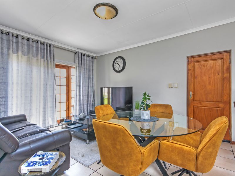 Open plan living and dining area featuring tiled flooring, a wooden door, and a sliding glass door providing access to the exterior.
