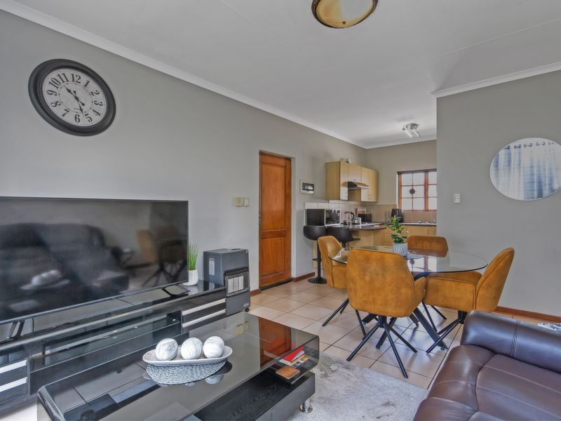 Open-plan living and dining area featuring tiled flooring, neutral wall tones, and a functional kitchen space with built-in cabinetry.