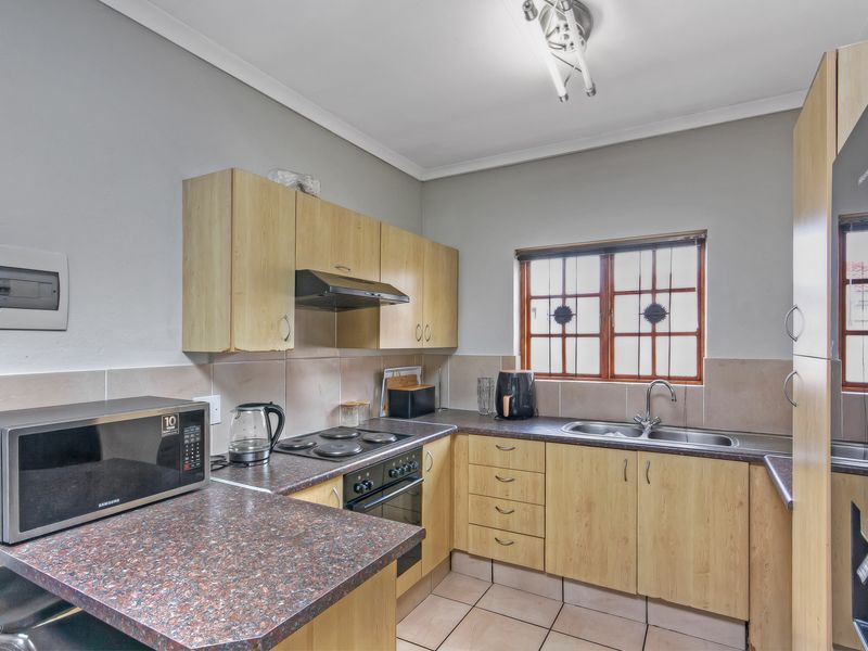Functional kitchen featuring laminate cabinetry, dark countertops, built-in oven with hob, extractor fan, and a stainless steel double sink.