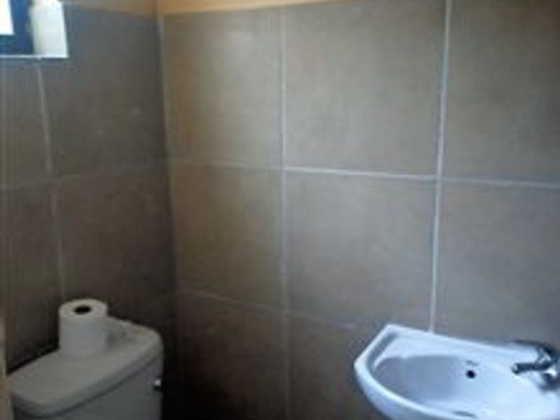 A compact bathroom featuring tiled walls, a pedestal basin, and a standard toilet.