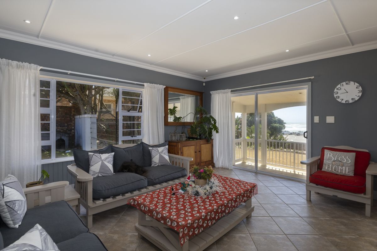 A bright and spacious living room featuring tiled flooring, recessed lighting, and large sliding glass doors that open to an outdoor patio area.