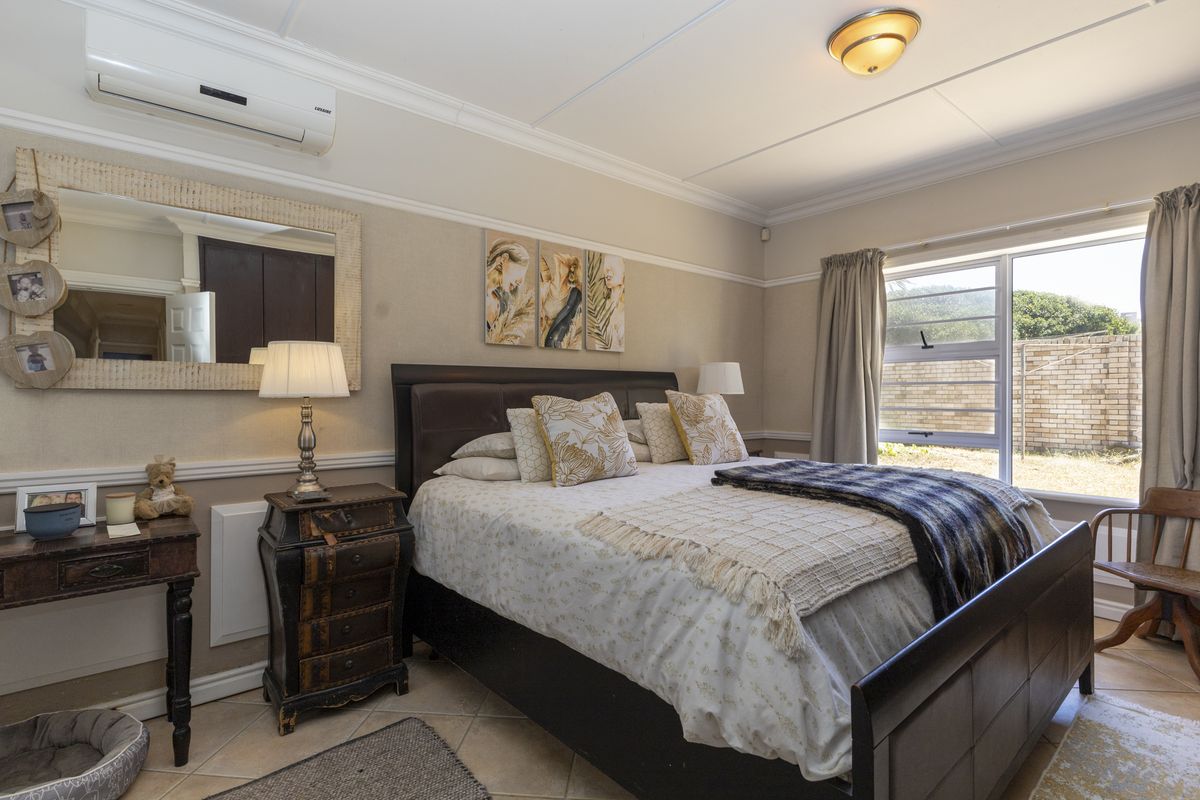 A well-maintained bedroom featuring tiled flooring, a split-system air conditioner, and a large window allowing natural light.