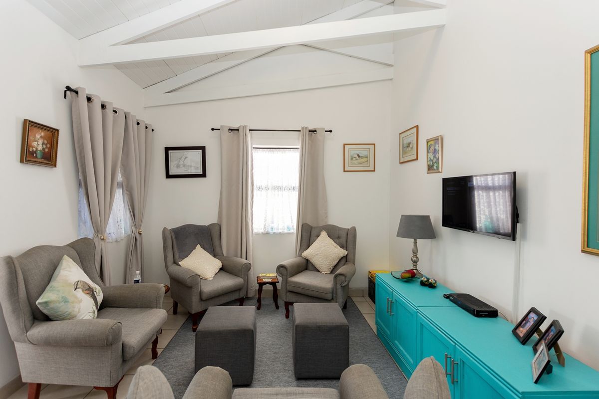 A cozy living room featuring a vaulted ceiling with exposed timber beams and neutral tiled flooring, offering a bright and comfortable atmosphere.