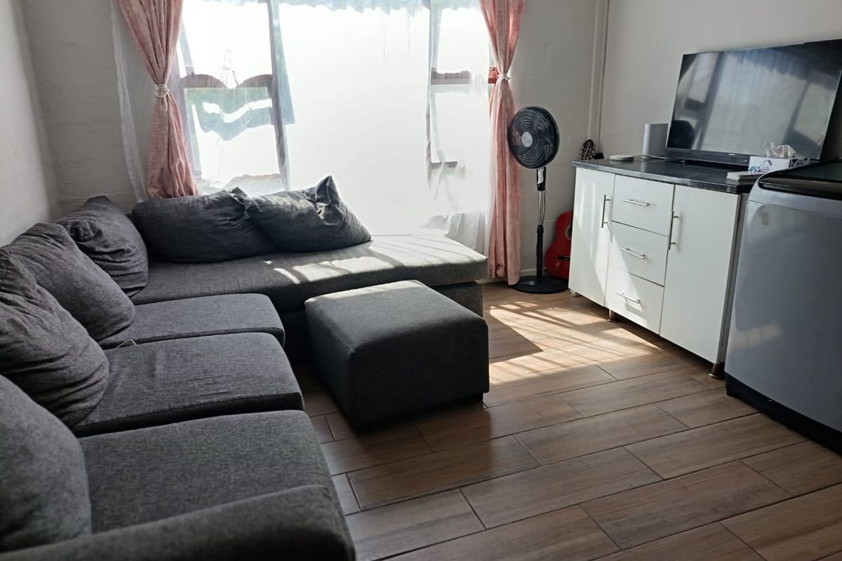 A living room featuring wood-look tile flooring and a large window that provides natural light.