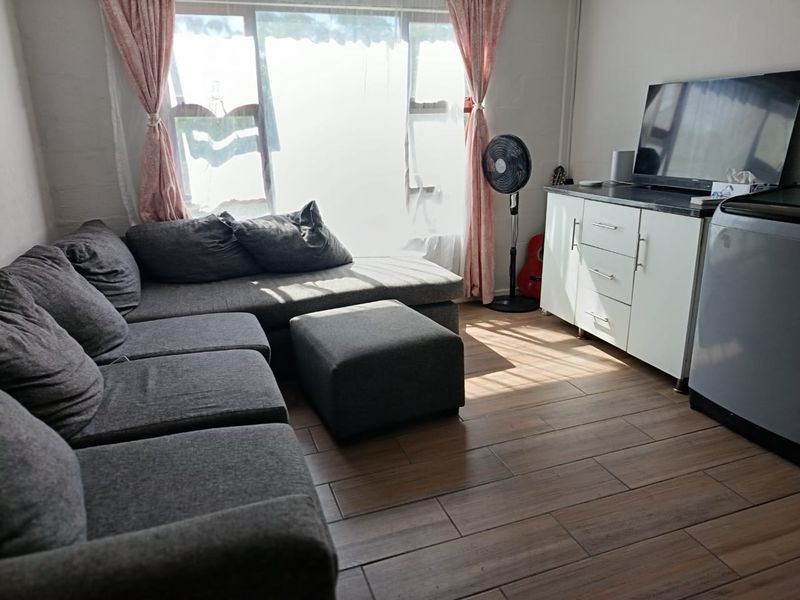 A living room featuring wood-look tile flooring and a large window that provides natural light.