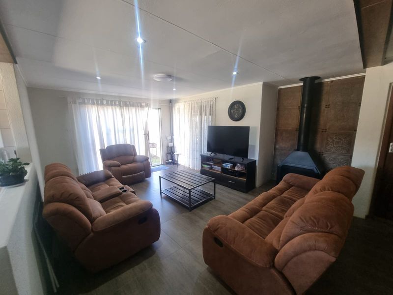 A comfortable living room featuring tiled flooring, recessed lighting, and a prominent black freestanding fireplace, with direct access to the outdoor area via sliding doors.