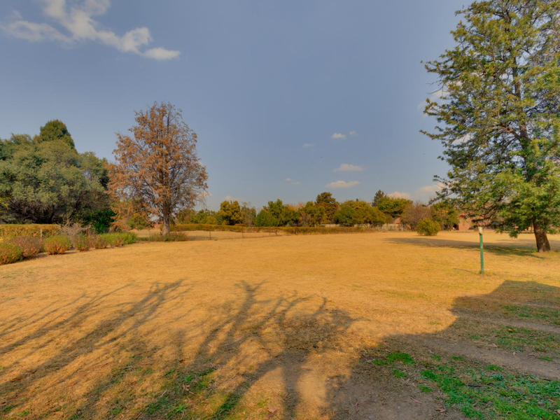 A spacious, open residential plot featuring established trees and natural grass, offering a blank canvas for future development or landscaping.