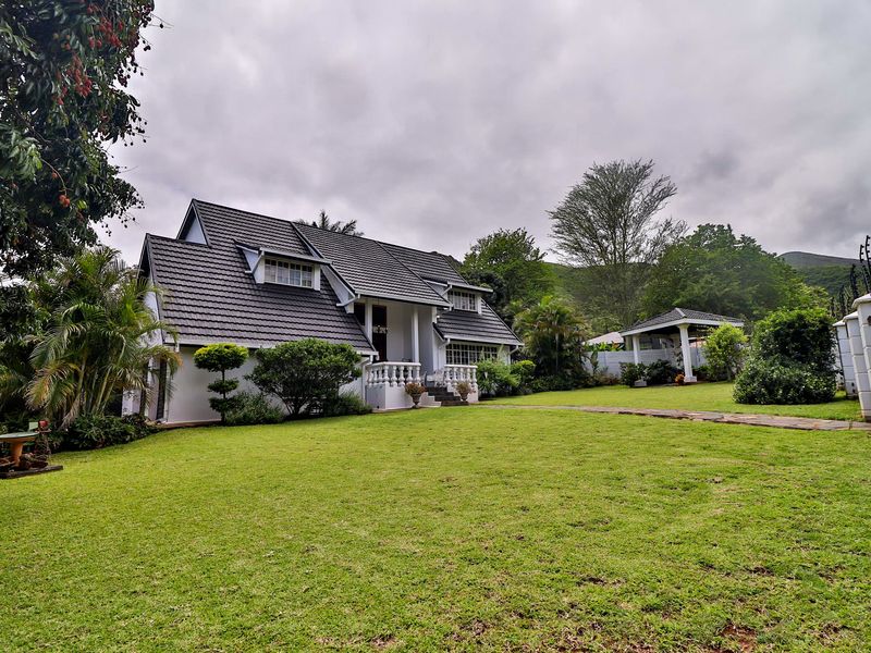 A well-maintained residential property featuring a tiled roof, classic balustrade entrance, and a spacious front garden with a stone pathway.