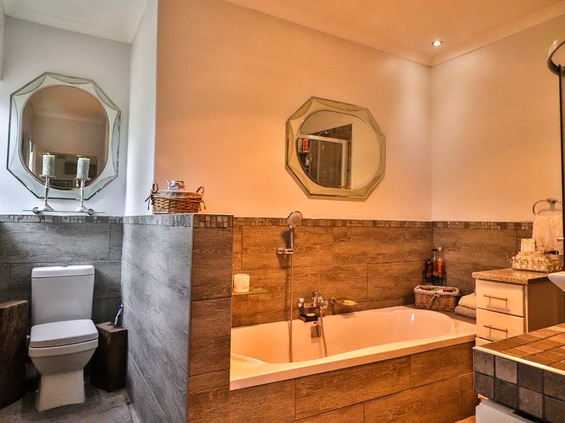 A well-appointed bathroom featuring a built-in bathtub, modern vanity with vessel sink, and stylish wood-look tiled wall finishes.