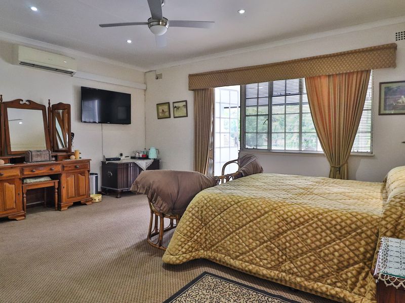 Spacious bedroom featuring carpet flooring, a ceiling fan, recessed lighting, and a wall-mounted air conditioning unit with access to natural light.