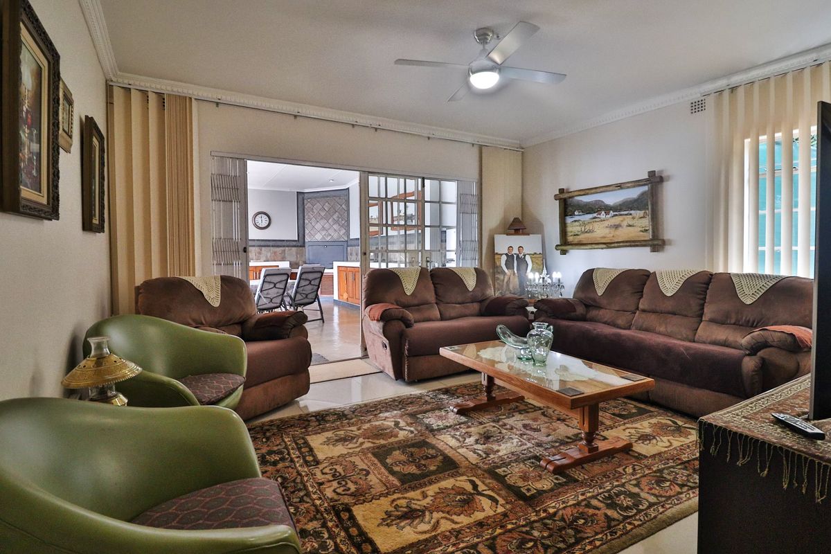 Spacious living room featuring tiled flooring, ceiling fan, and sliding glass doors providing access to an adjacent indoor patio area.