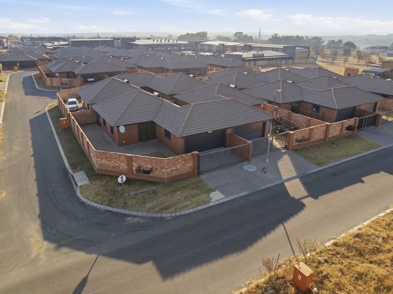Aerial view of a residential estate featuring facebrick houses with tiled roofs, paved driveways, and secure perimeter walling.