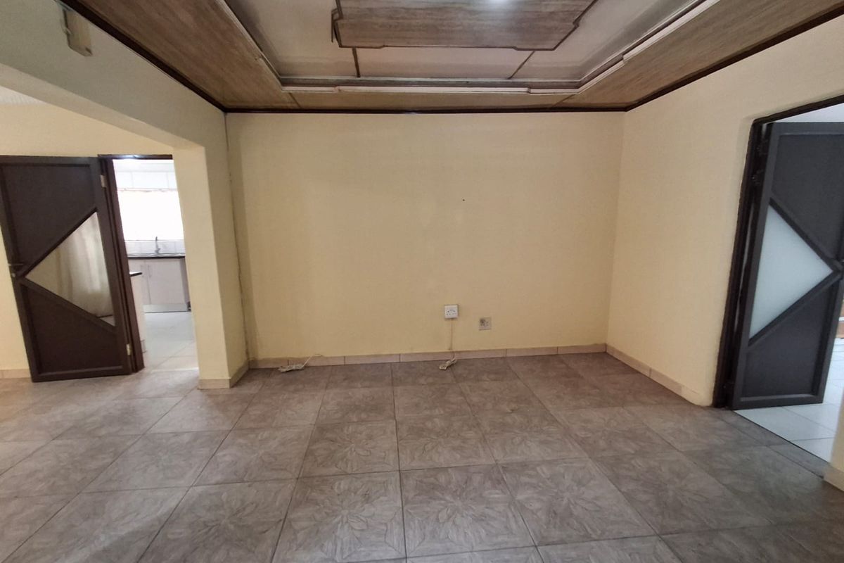An empty living room featuring tiled flooring and a recessed ceiling detail, providing a neutral space ready for personalization.