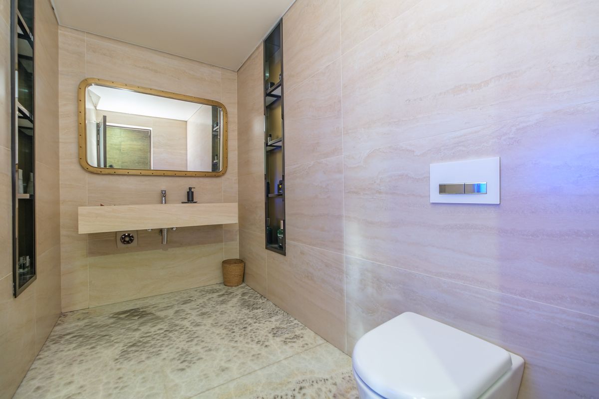 Modern bathroom featuring a wall-mounted vanity, integrated shelving, and a concealed cistern toilet with high-quality stone tiling throughout.