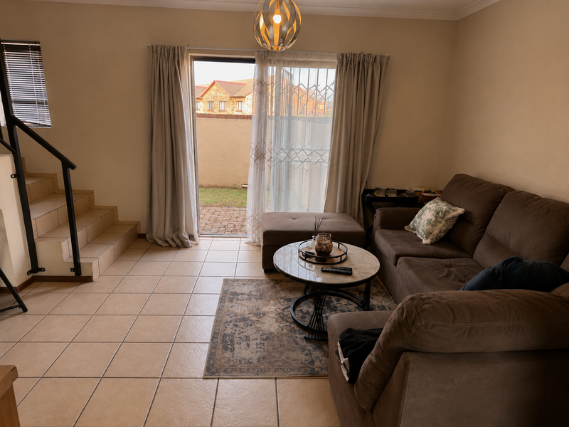 A living room featuring tiled flooring, a staircase with a metal railing, and a sliding glass door providing access to the rear patio area.