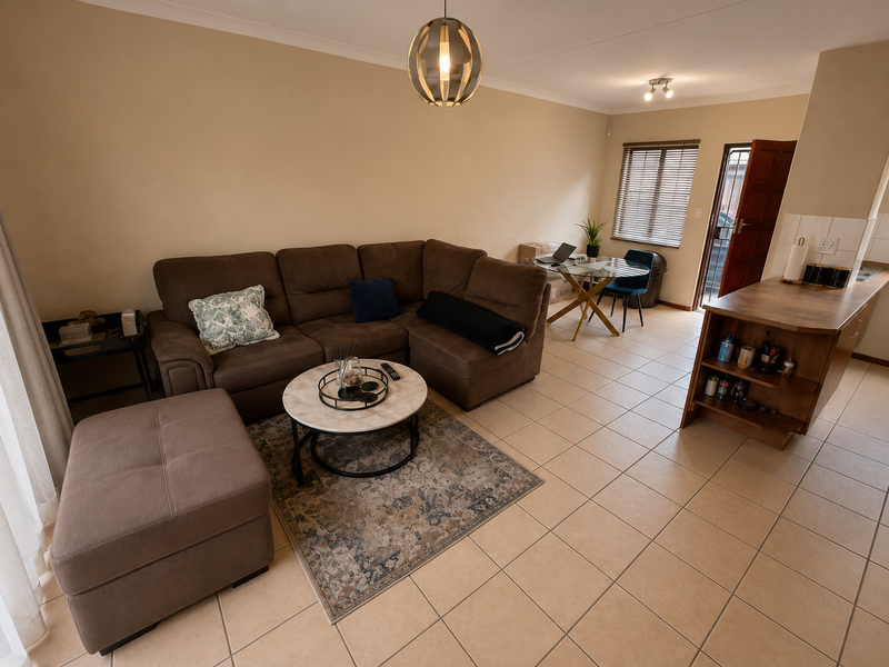 Open-plan living area featuring tiled flooring, a kitchen breakfast bar, and neutral wall tones, providing a functional and connected space.