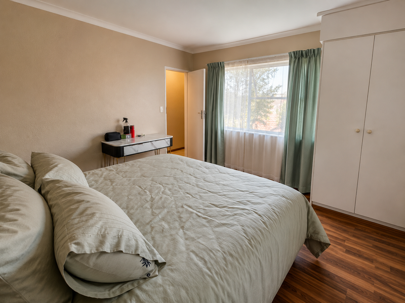 A well-maintained bedroom featuring laminate flooring, a built-in wardrobe, and neutral wall finishes, offering a comfortable and functional living space.