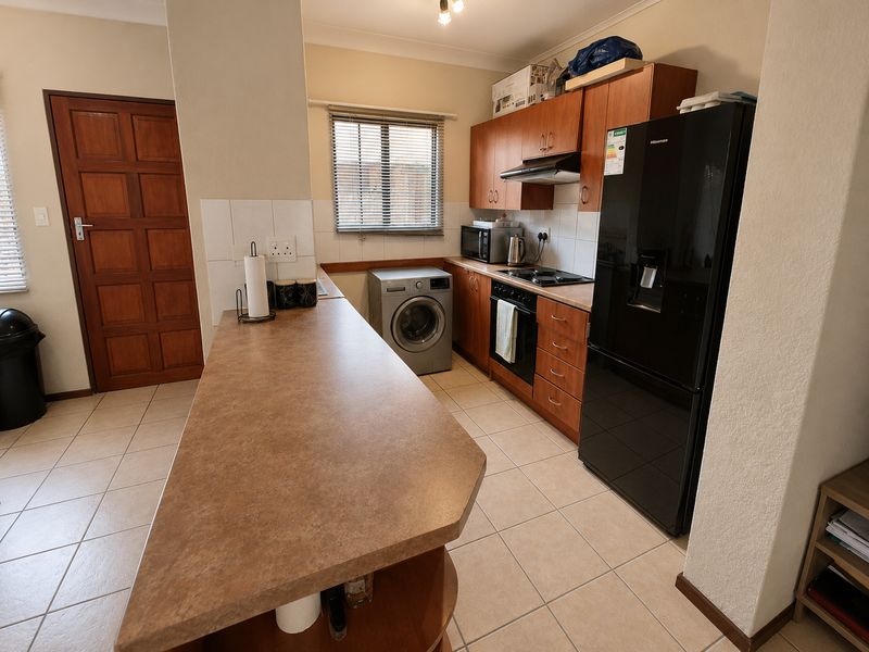 Functional kitchen featuring laminate countertops, built-in cabinetry, integrated oven and hob, tiled flooring, and a solid timber door.