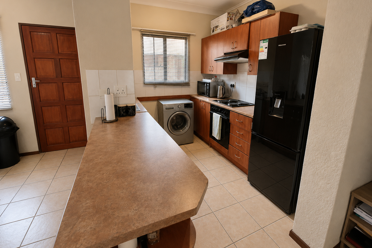 Functional kitchen featuring laminate countertops, built-in cabinetry, integrated oven and hob, tiled flooring, and a solid timber door.