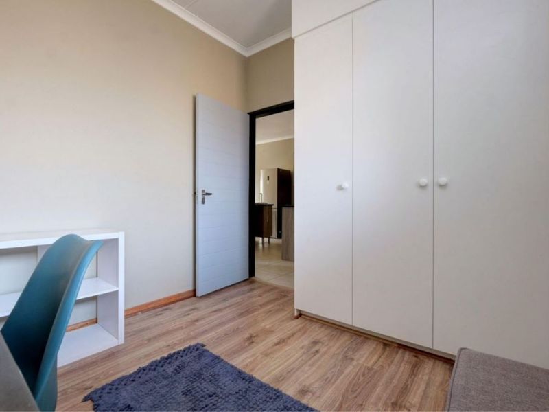 A well-maintained bedroom featuring laminate flooring, neutral wall finishes, and ample built-in cupboard storage space.