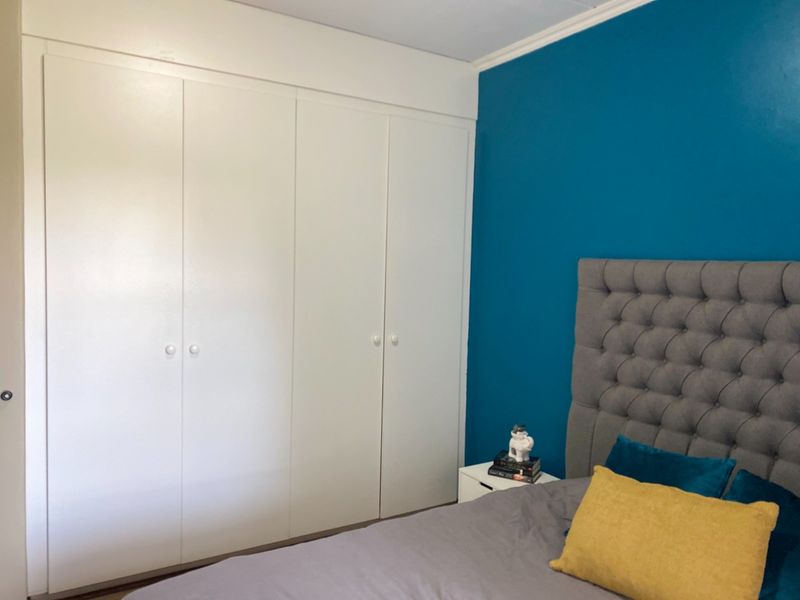 A bedroom featuring a large white built-in wardrobe with classic cabinetry and a bold blue accent wall.