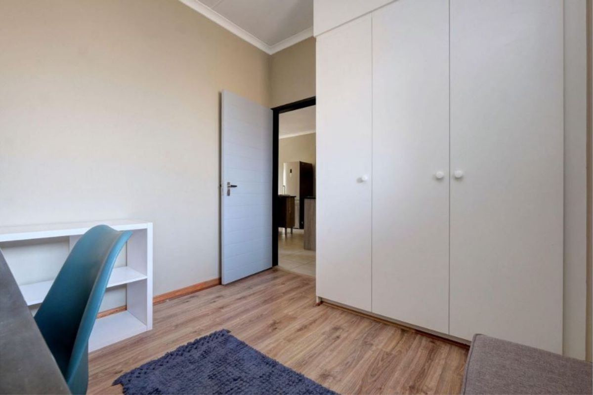 A well-maintained bedroom featuring laminate flooring, neutral wall finishes, and ample built-in cupboard storage space.