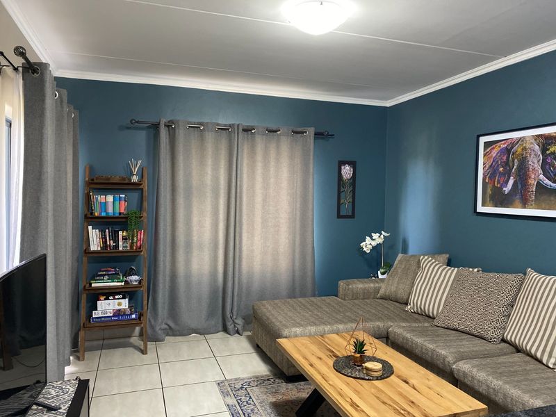 A comfortable living room featuring tiled flooring, crown molding, and dark blue accent walls, creating a cozy and well-maintained living space.