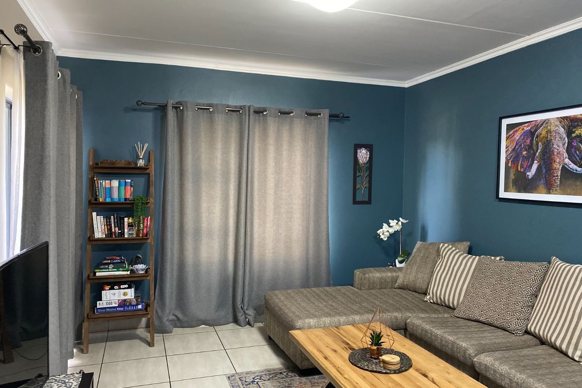 A comfortable living room featuring tiled flooring, crown molding, and dark blue accent walls, creating a cozy and well-maintained living space.