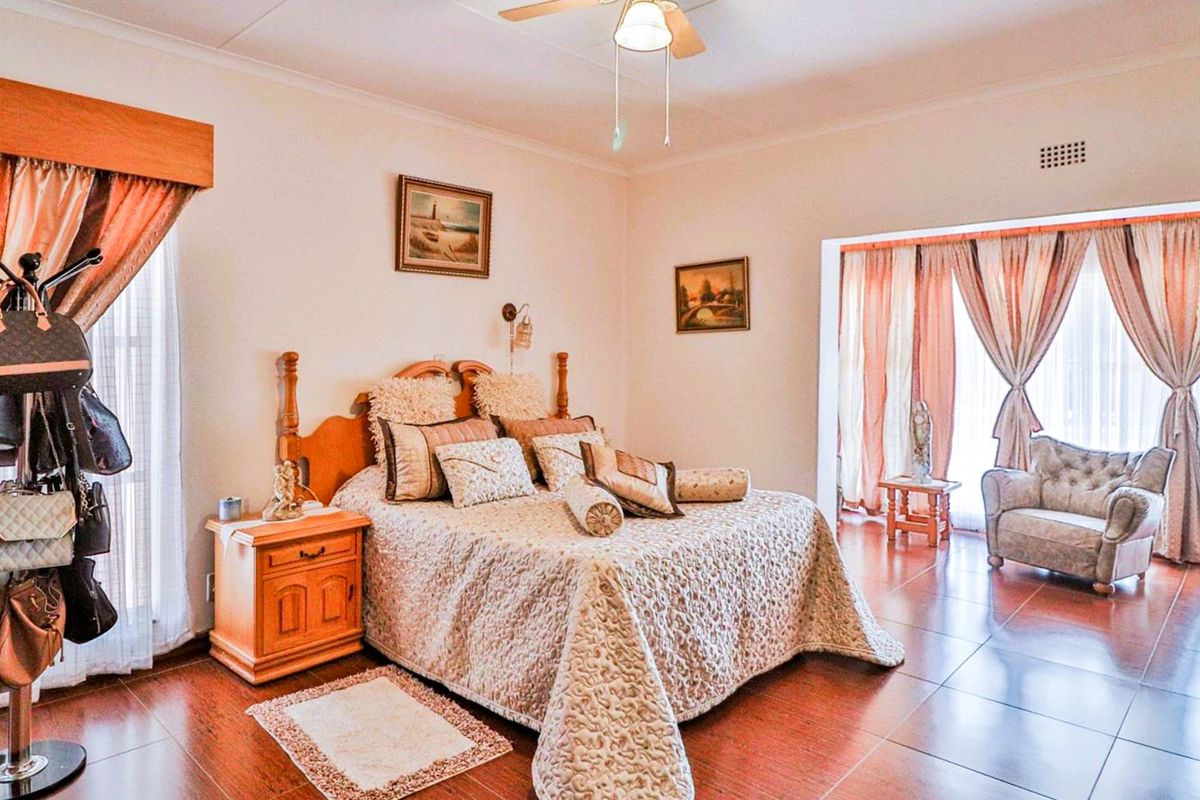 Spacious bedroom featuring tiled flooring, a ceiling fan, and large windows with curtains, providing ample natural light and a comfortable living space.