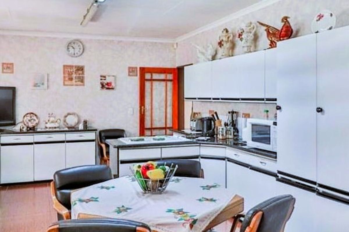 A functional kitchen featuring white cabinetry, integrated storage, and a central dining area, offering a practical layout for daily meal preparation.