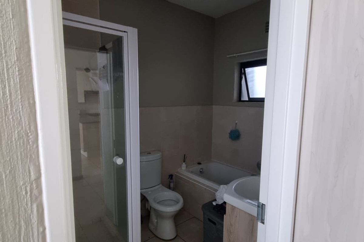 A functional bathroom featuring a shower enclosure, bathtub, toilet, and vanity basin with neutral wall finishes and tiled flooring.