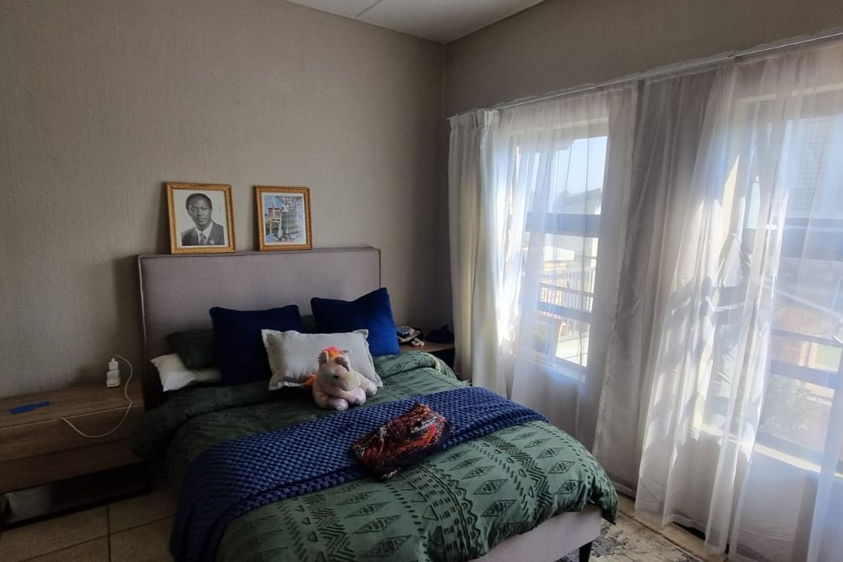 A functional bedroom featuring tiled flooring and large windows that allow for ample natural light.