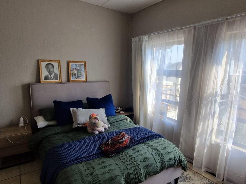 A functional bedroom featuring tiled flooring and large windows that allow for ample natural light.