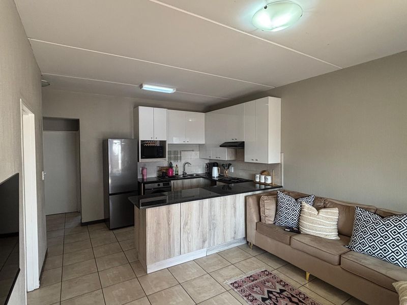 Open-plan living area featuring a modern kitchen with granite countertops, built-in cabinetry, and tiled flooring throughout the space.